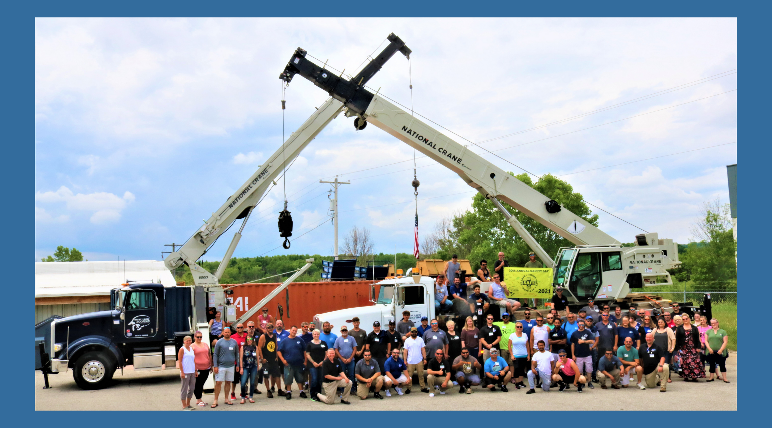 Large group of Great Lakes Roof staff standing together in front of two of our cranes in honor of Safety Day