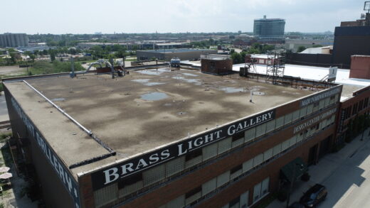 Brass Light Gallery iconic building signage visible from the highway on the section of ballasted commercial roof that was not replaced